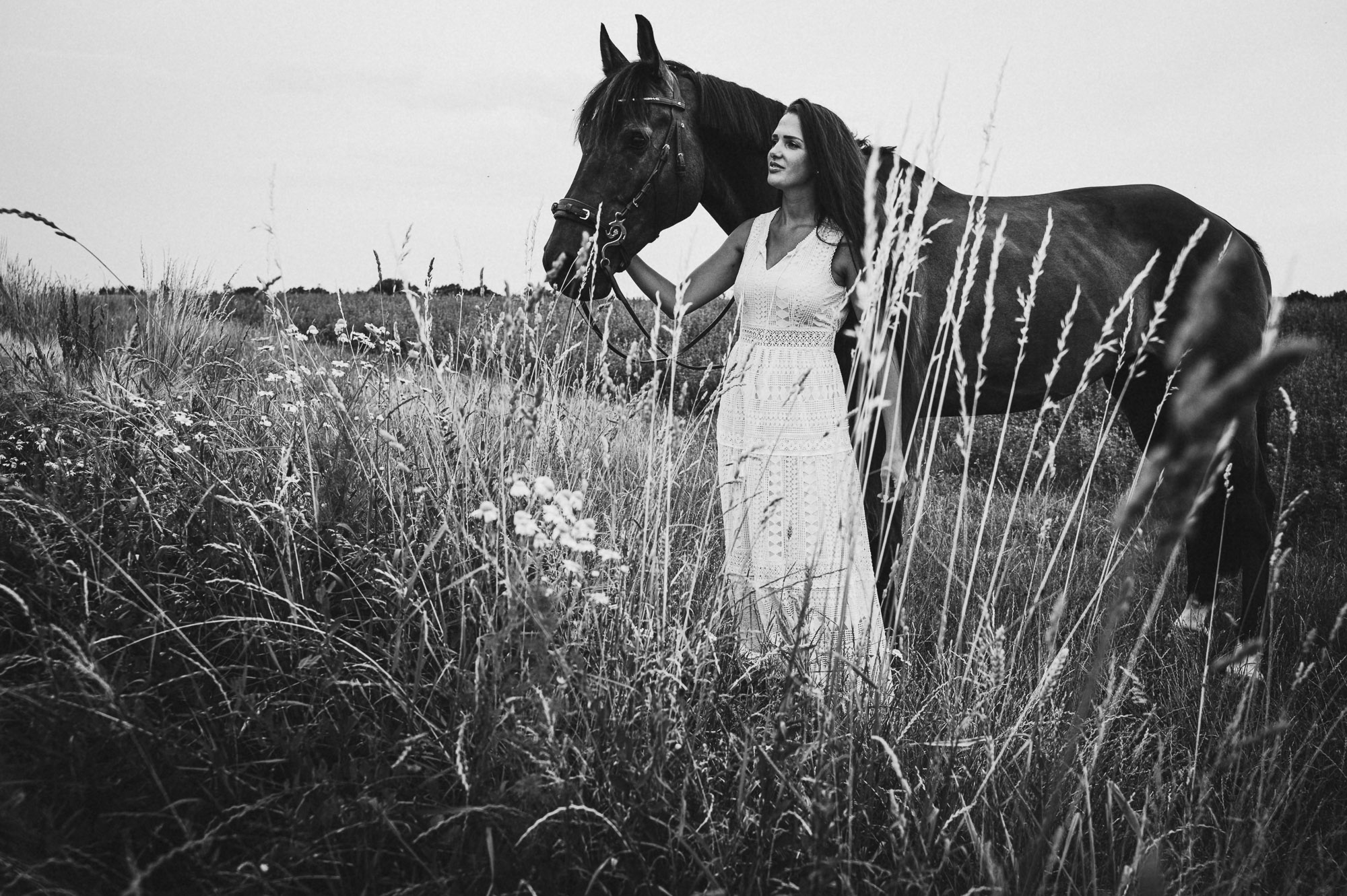 junge Frau langes Kleis outdoor Pferd in der Wiese schwarzweiss Pferdeshooting outdoor